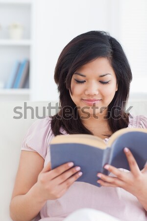 Woman sitting on a sofa while she holds a book in a living room Stock photo © wavebreak_media