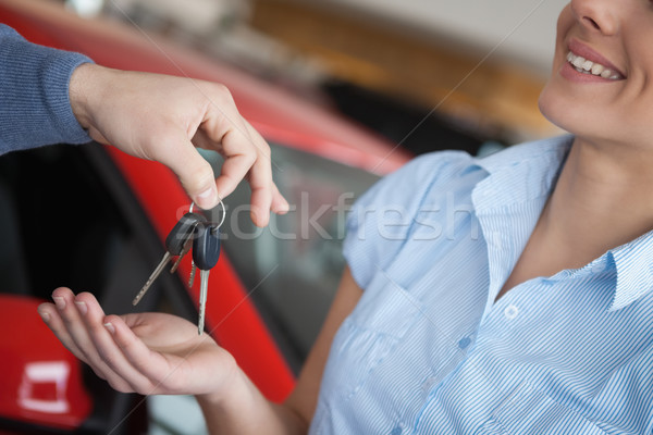 Smiling woman receiving keys from somebody in a car shop Stock photo © wavebreak_media