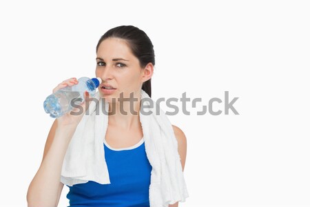Sportswoman with a towel drinking water against white background Stock photo © wavebreak_media