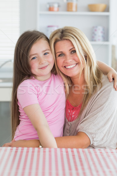 Girl sitting on mother's lap in the kitchen Stock photo © wavebreak_media