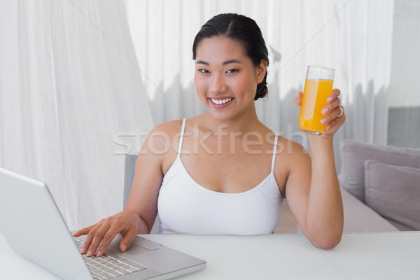 Feliz mujer usando la computadora portátil jugo de naranja casa salón Foto stock © wavebreak_media