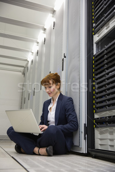Technician sitting on floor beside server tower using laptop Stock photo © wavebreak_media