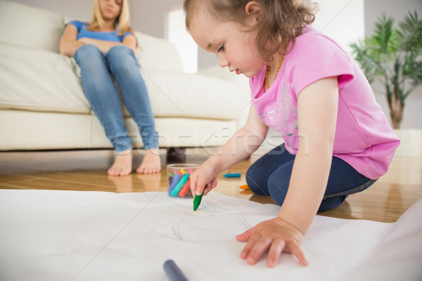 Girl drawing in the living room with mother sitting behind Stock photo © wavebreak_media