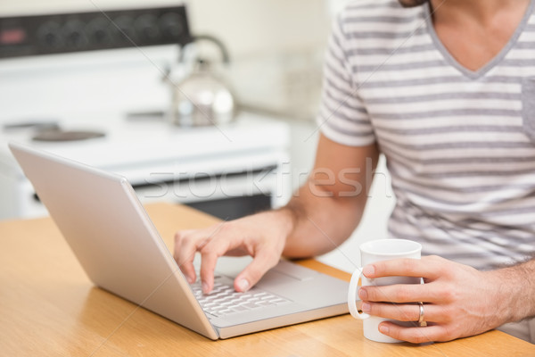 Jeune homme utilisant un ordinateur portable café maison cuisine ordinateur Photo stock © wavebreak_media