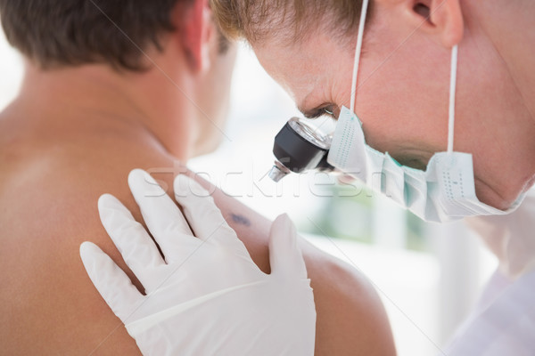 Stock photo: Doctor examining a spot at his patient 