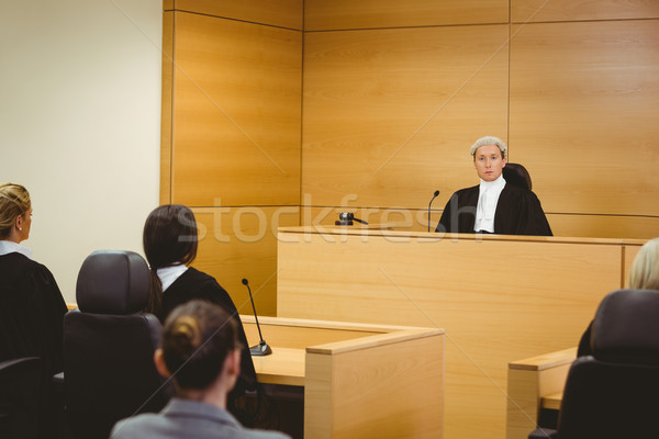 Stock photo: Unsmiling judge wearing wig with american flag behind him