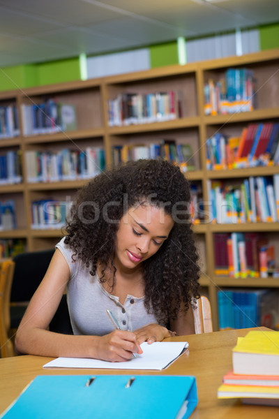 Stock photo: Student writing notes in notepad in the library