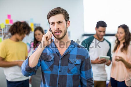 Portrait of man sitting on chair with friends discussing in background Stock photo © wavebreak_media