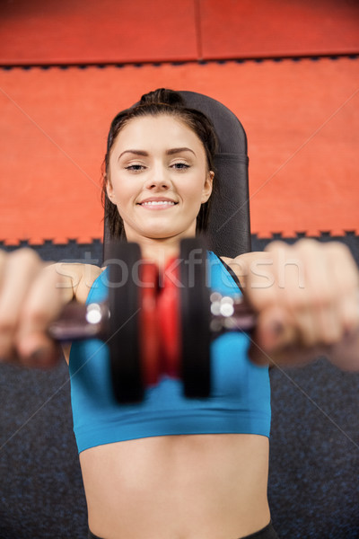 Fókuszált nő emel súlyzók fekszik tornaterem Stock fotó © wavebreak_media
