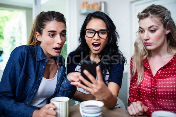 Feminino amigos olhando telefone móvel jovem Foto stock © wavebreak_media