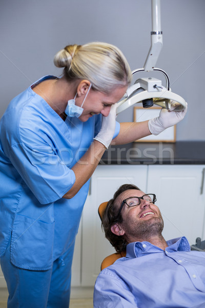 Smiling dentist assistant adjusting light over patients mouth Stock photo © wavebreak_media