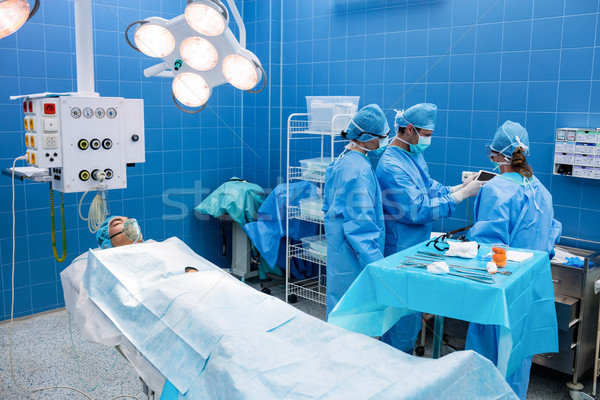 Surgeons using digital tablet and patient lying on operation bed Stock photo © wavebreak_media