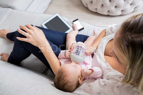 Mother feeding her baby with milk bottle in living room Stock photo © wavebreak_media