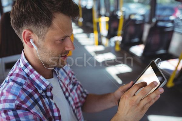 Homem bonito escuta música digital comprimido ônibus Foto stock © wavebreak_media