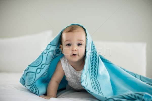 Stock photo: Cute baby girl under the blanket on bed