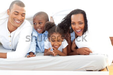 Happy family having fun lying down on bed at home Stock photo © wavebreak_media