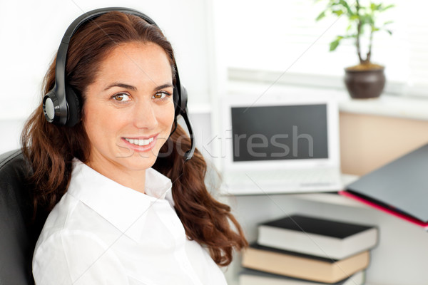 Stock photo: Delighted businesswoman with headset sitting at her desk