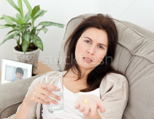 Tired woman taking her medicine lying on the sofa at home Stock photo © wavebreak_media