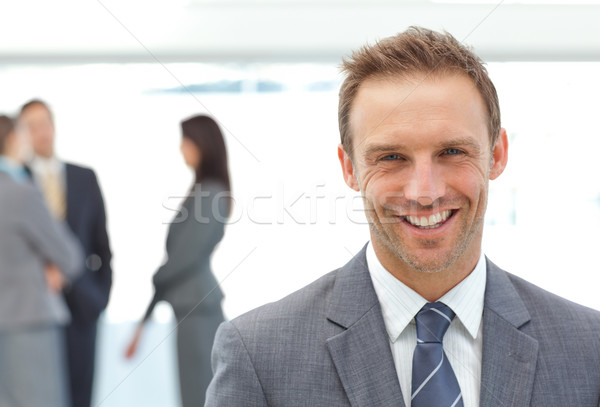 Happy businessman posing in front of his team while working on the background Stock photo © wavebreak_media