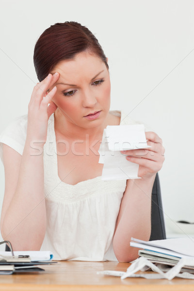 Young attractive red-haired female being depressed by the amount of the receipt while sitting at a d Stock photo © wavebreak_media