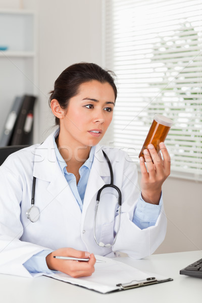 Beautiful worried doctor holding a box of pills in her office Stock photo © wavebreak_media