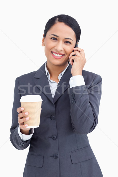 Close up of smiling saleswoman with paper cup and cellphone against a white background Stock photo © wavebreak_media