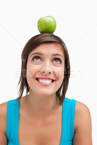 Smiling teenage girl looking up while trying to see the green apple on her head Stock photo © wavebreak_media