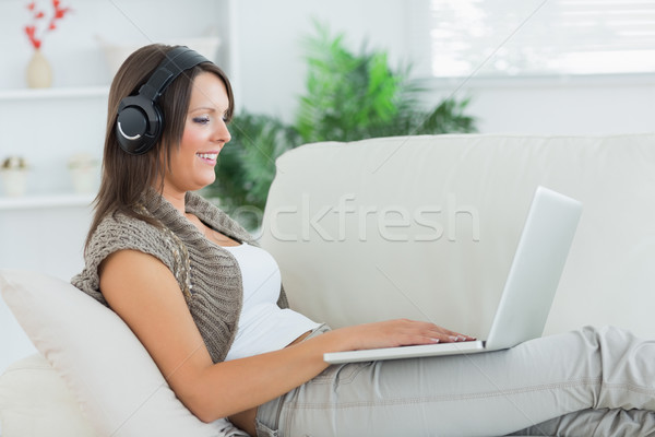Feliz mulher escuta música laptop sofá Foto stock © wavebreak_media