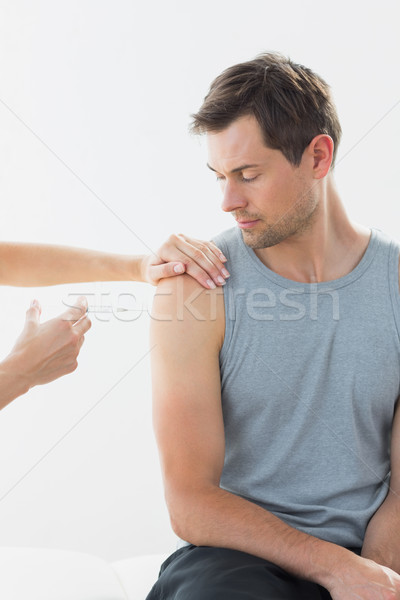 Doctor injecting man on arm in clinic Stock photo © wavebreak_media