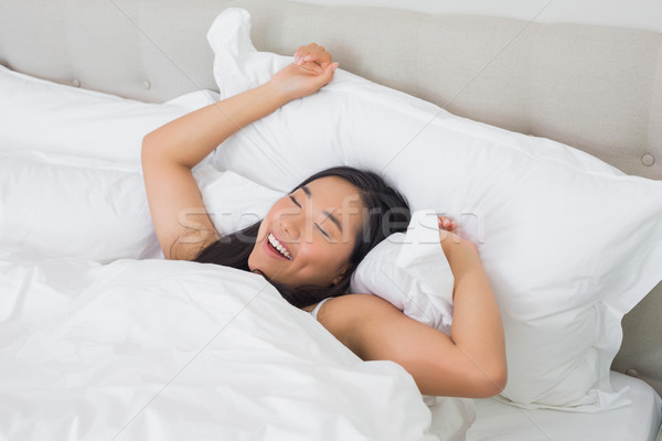 Femeie zambitoare pat dimineaţă acasă dormitor femeie Imagine de stoc © wavebreak_media