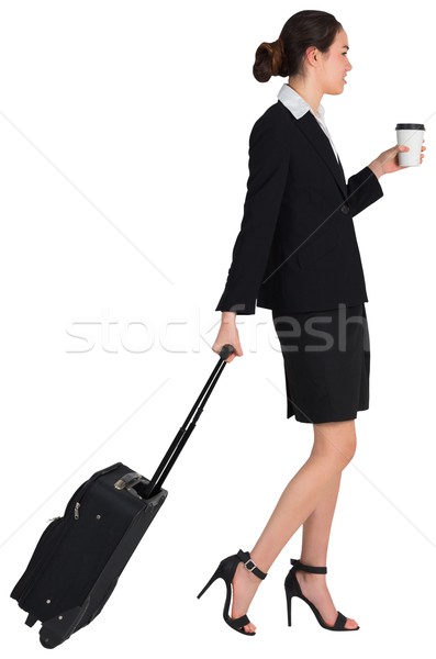 Stock photo: Businesswoman pulling her suitcase holding coffee