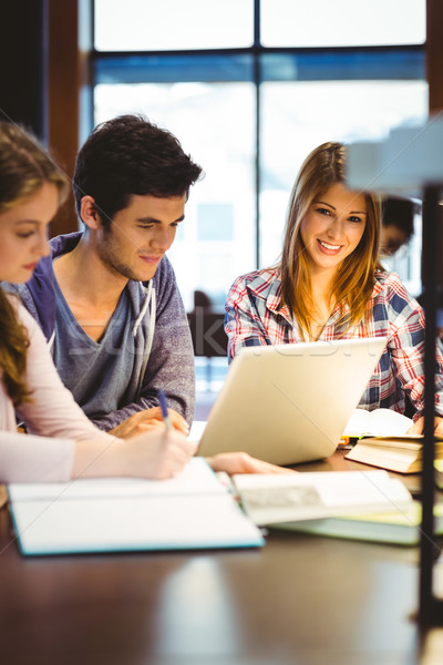Stock photo: Student looking at camera while studying with classmates