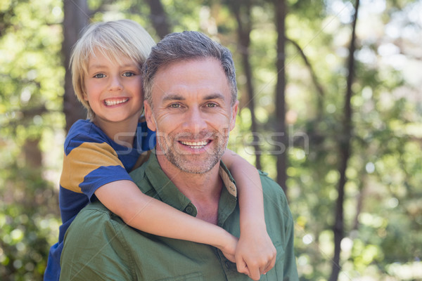 Stock photo: Smiling father piggybacking son in forest