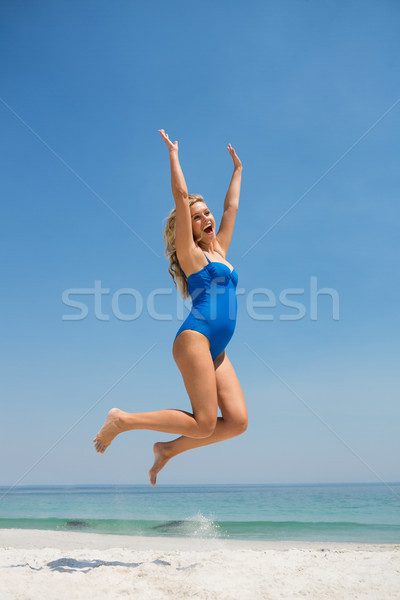 Cheerful woman jumping on sand at beach Stock photo © wavebreak_media