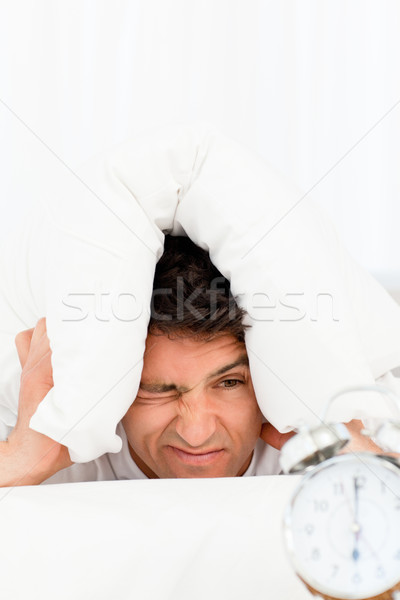 Stock photo: Handsome man lying on his bed and looking at his clock at morning