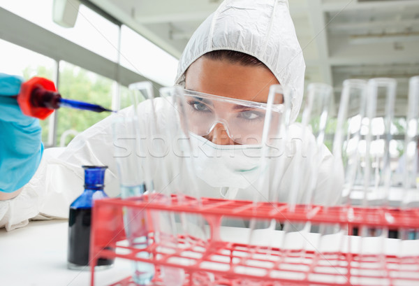 Protected female science student dropping blue liquid in a test tube in a laboratory Stock photo © wavebreak_media