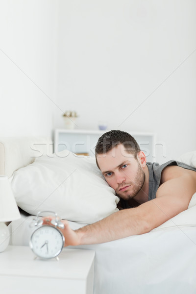 Portrait of a handsome man being awakened by an alarm clock in his bedroom Stock photo © wavebreak_media