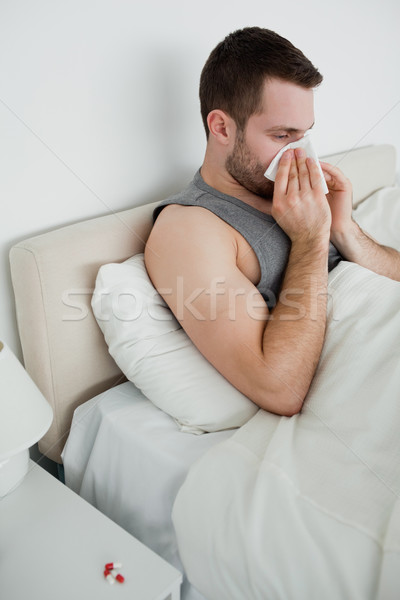 Portrait of a man blowing his nose in his bedroom Stock photo © wavebreak_media