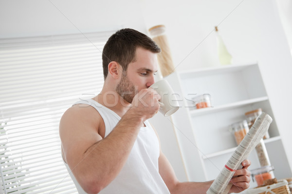Young man drinking tea while reading the news in his kitchen Stock photo © wavebreak_media