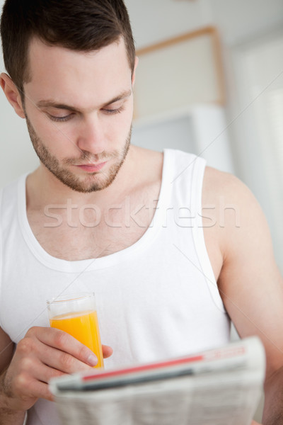 Portrait of a beautiful man drinking orange juice while reading the news in his kitchen Stock photo © wavebreak_media