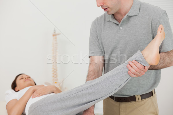 Brunette woman lying while a therapist is stretching her leg indoors Stock photo © wavebreak_media