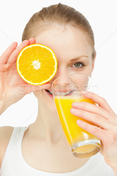 Woman placing an orange on her eye while drinking in a glass against white background Stock photo © wavebreak_media