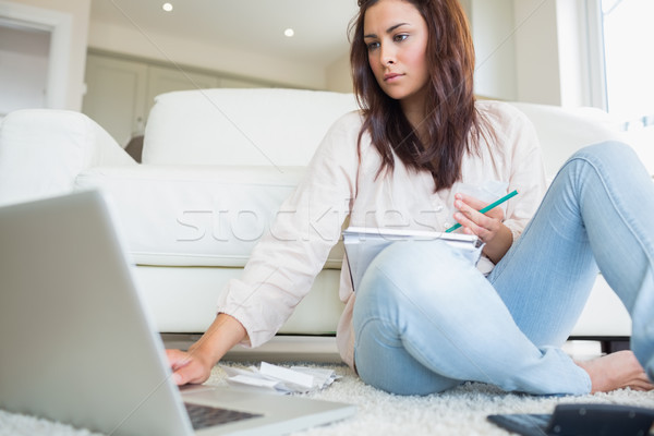 Woman typing on the ;laptop and comparing bills on floor of living room Stock photo © wavebreak_media