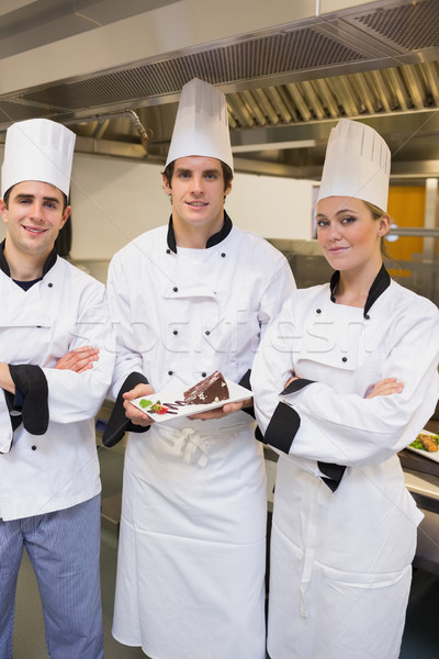 Three happy Chef's presenting a cake in the kitchen Stock photo © wavebreak_media