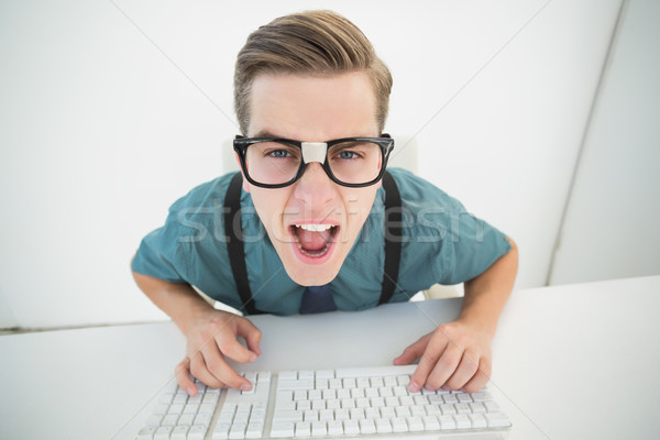 Casual angry businessman typing at his desk  Stock photo © wavebreak_media