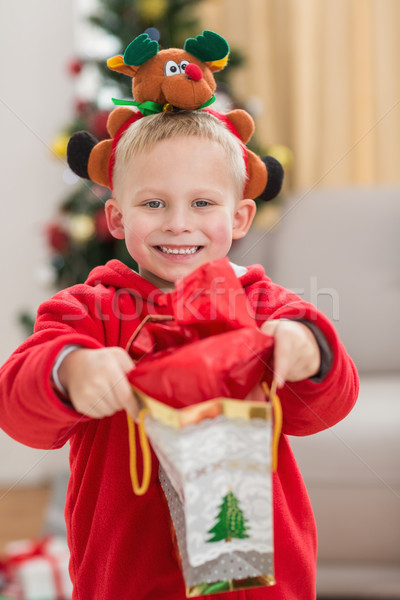 Festive little boy smiling at camera with gift Stock photo © wavebreak_media