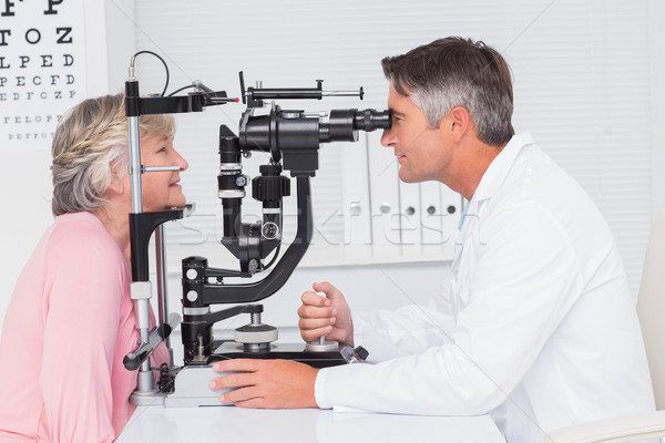 Optician examining senior patient through slit lamp Stock photo © wavebreak_media