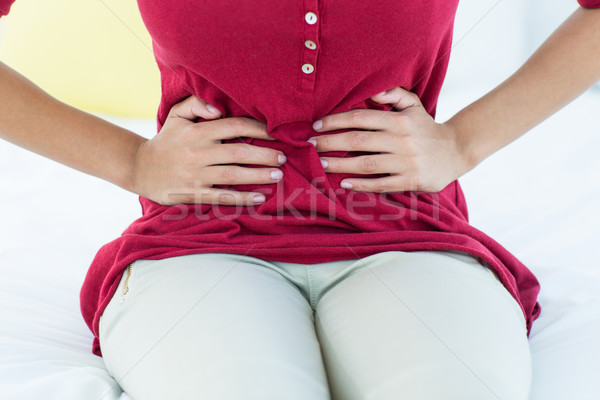 Femme séance lit estomac douleur maison [[stock_photo]] © wavebreak_media
