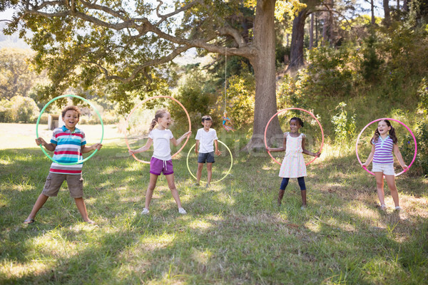 Stock photo: Group of cheerful friends playing with hula hoops at campsite