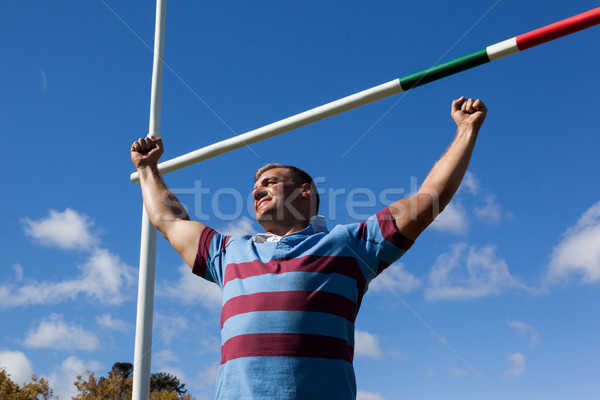 Low angle view of smiling rugby player with arms raised against blue sky Stock photo © wavebreak_media